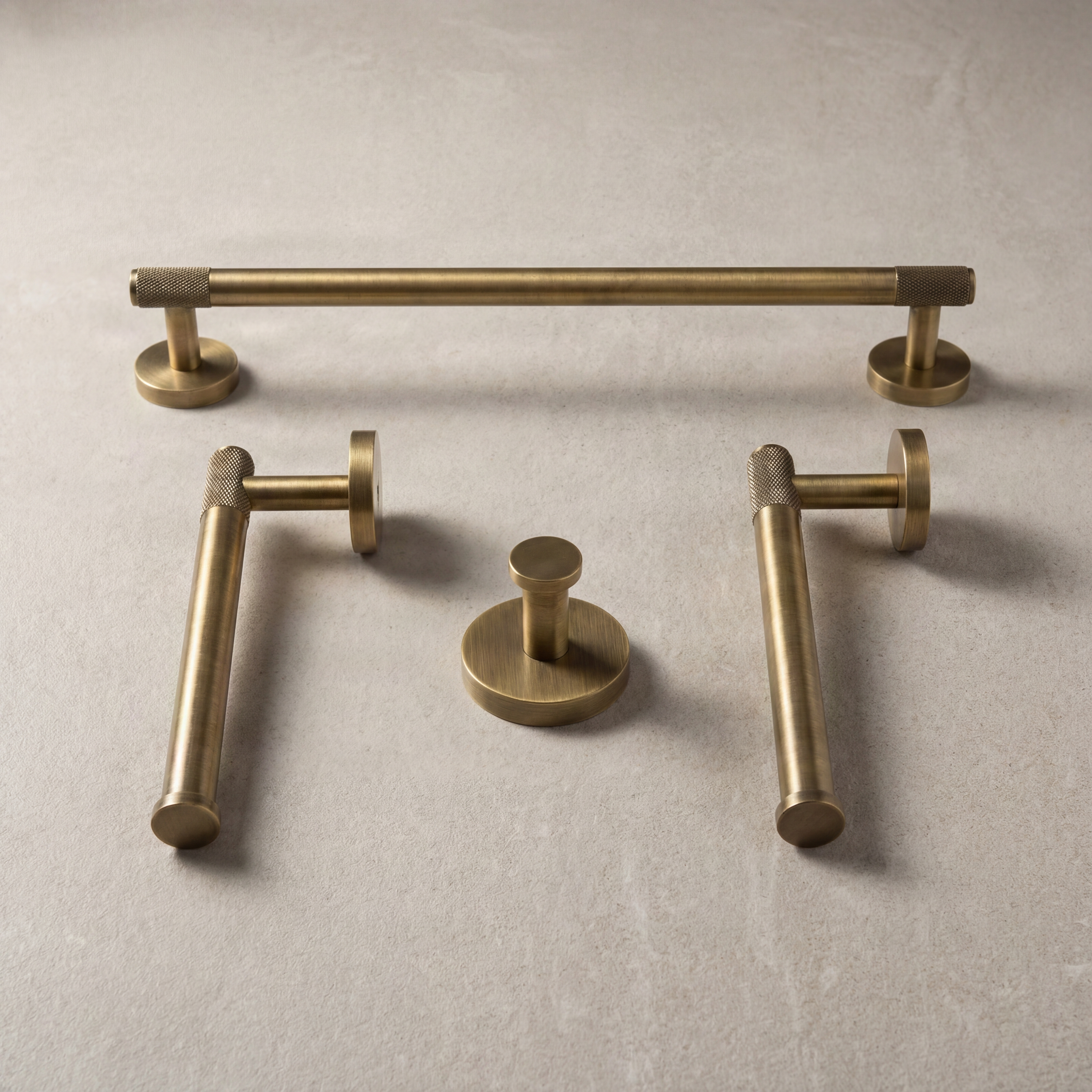 Collection of knurled aged brass bathroom fixtures on pale stone.