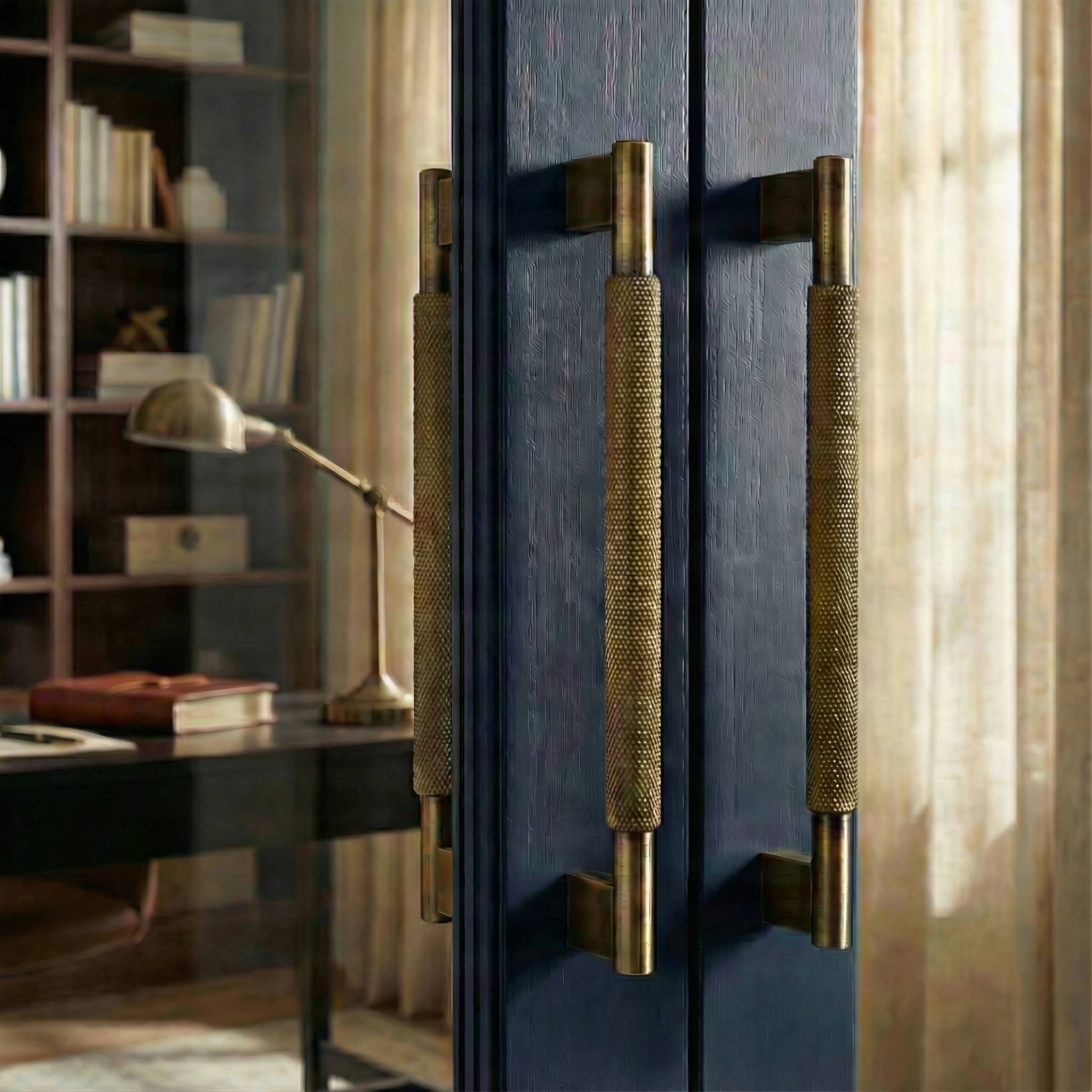 Knurled aged brass door handle 17 inch on a rich blue door, complementing a sophisticated library.