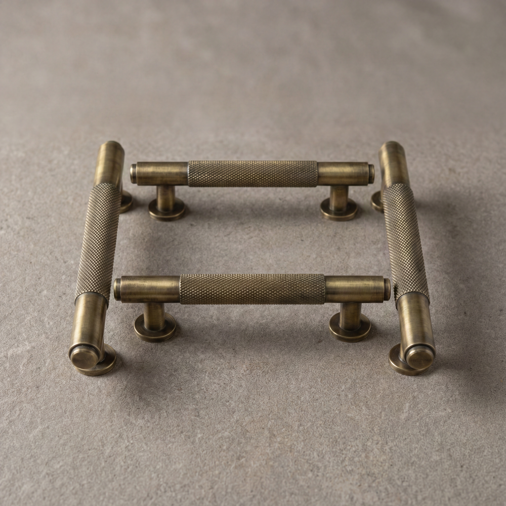 Four knurled aged brass door pulls on a stone surface
