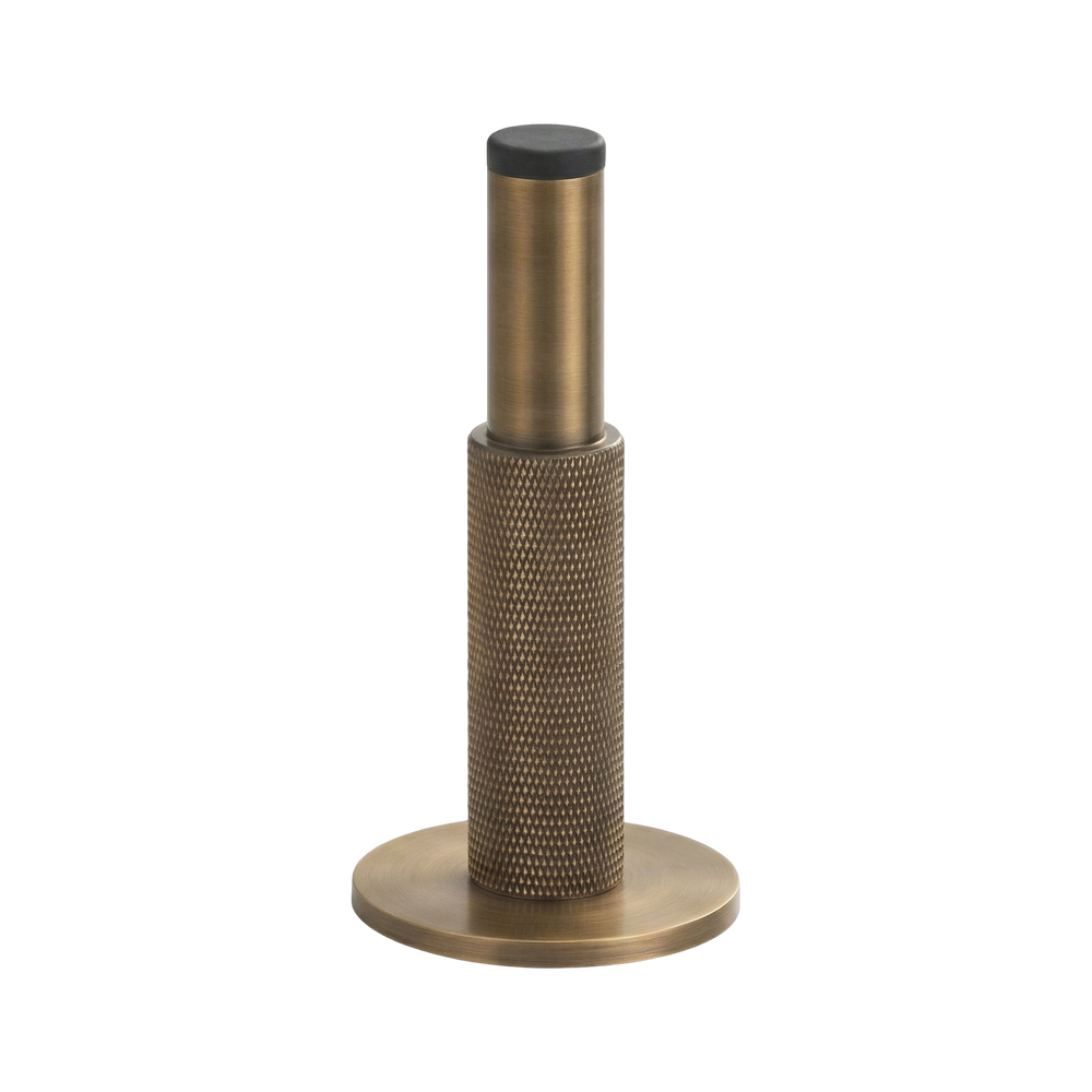Aged brass wall mount door stop, finely knurled for a tactile heirloom feel, with black buffer.