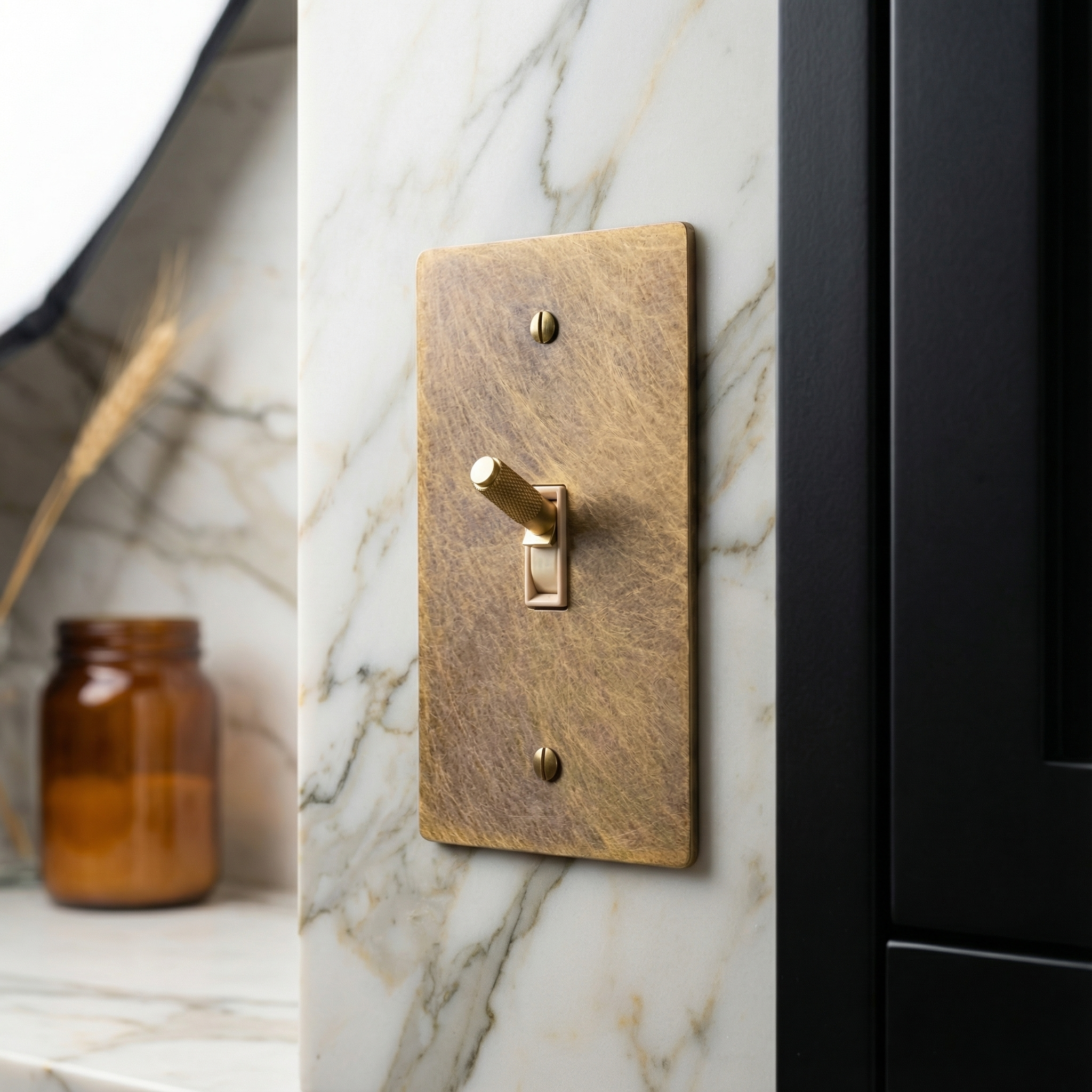 Elegant aged brass 1 gang toggle switch plate on veined marble, a tactile accent of timeless luxury.