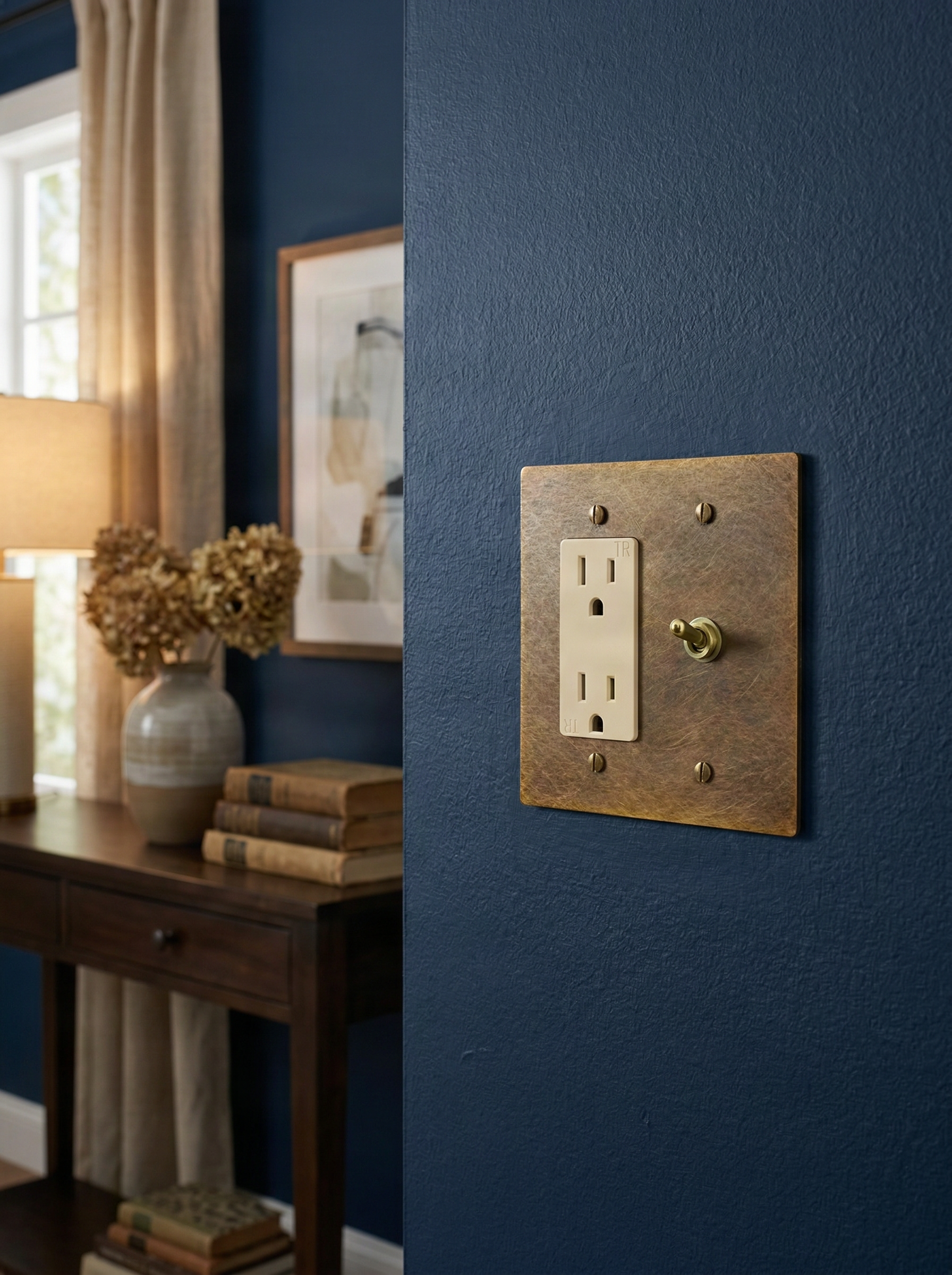 aged brass 2 gang duplex outlet and vintage toggle switch plate on a textured blue wall, exuding timeless luxury in a refined interior.
