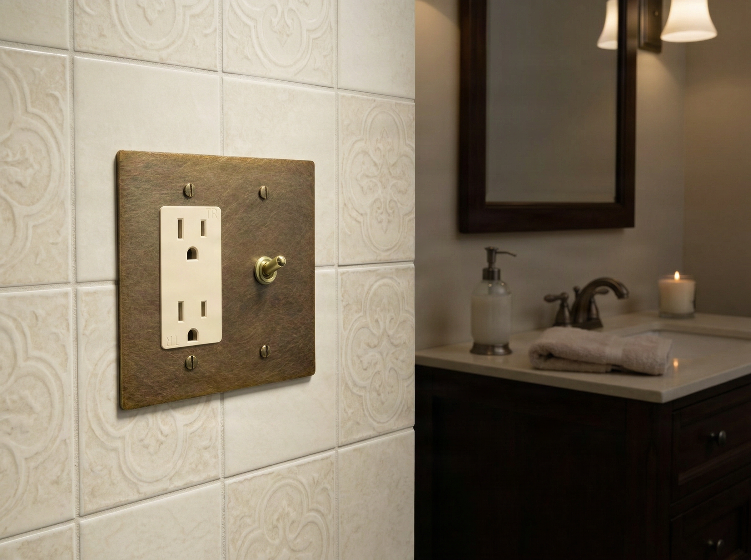 Aged brass 2 gang duplex outlet and vintage toggle switch plate, a timeless detail on luxurious bathroom tiles.