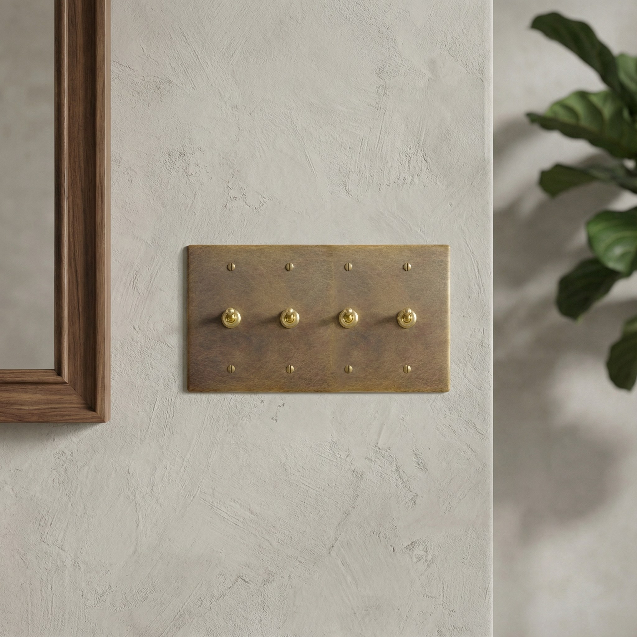 aged brass 4 gang vintage toggle switch plate on a textured wall, next to a wood mirror. Timeless luxury.