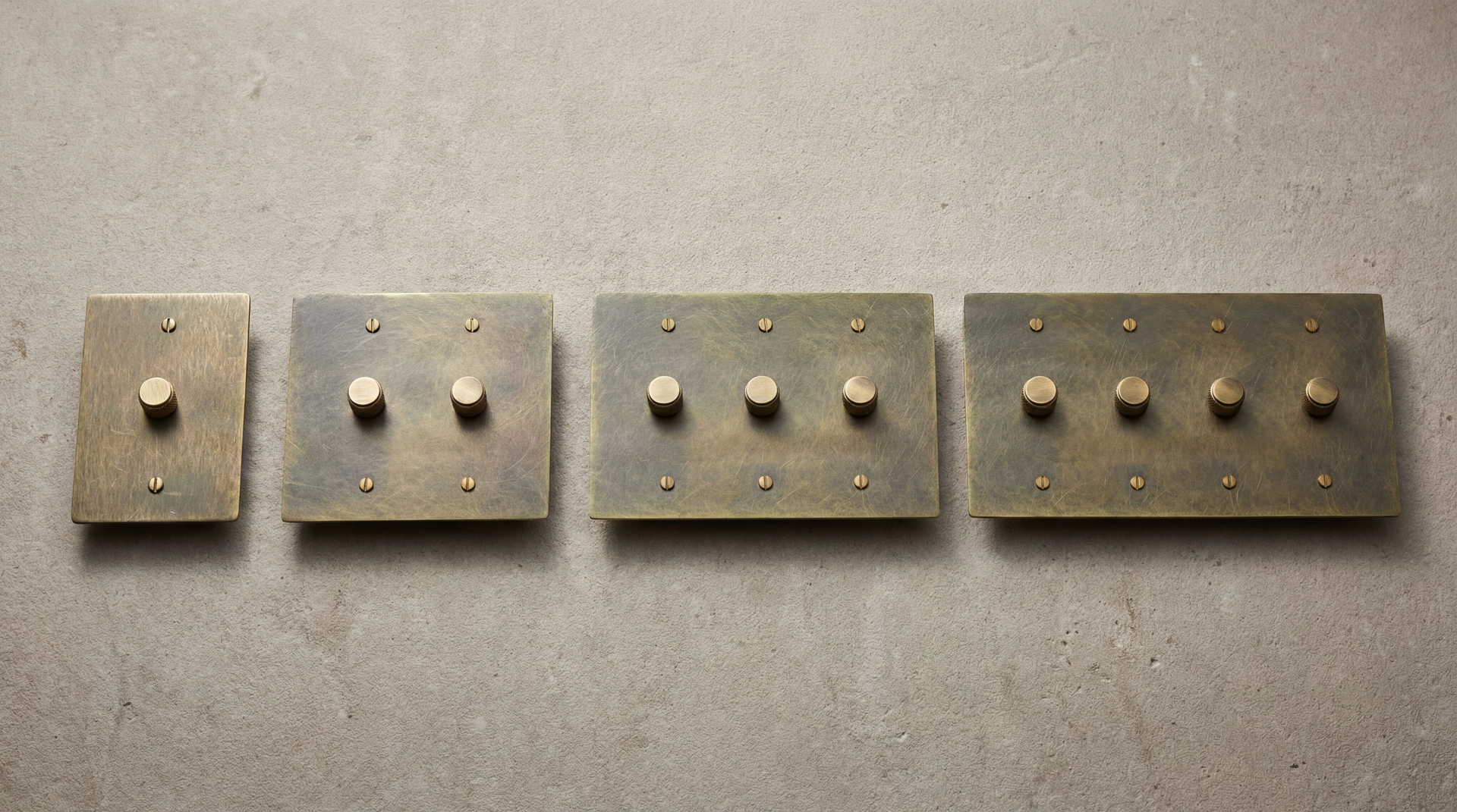 Collection of solid Antique Brass Dimmer Switches with knurled knobs, displaying heirloom quality on a textured wall.