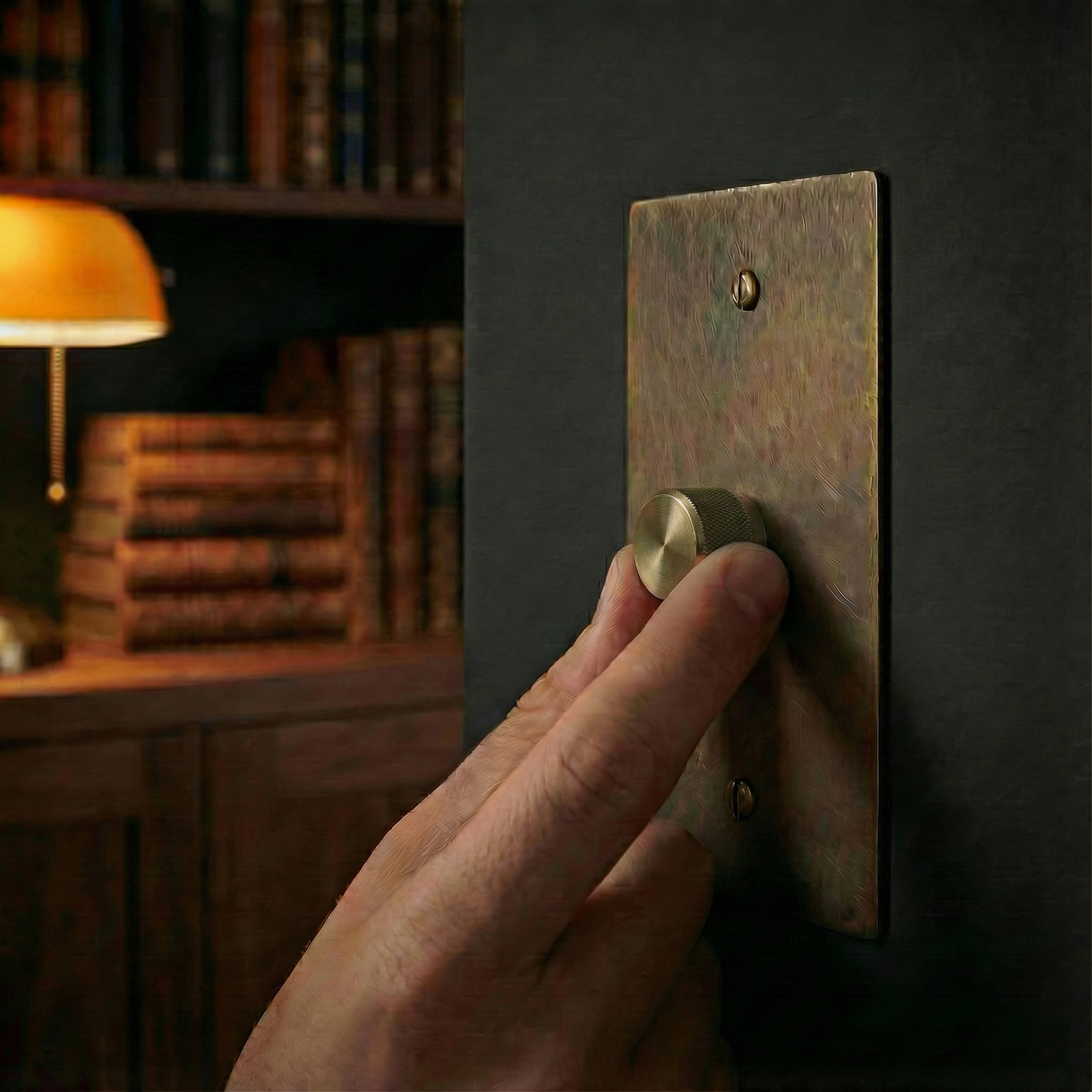 Hand adjusts an antique brass 1 gang dimmer switch plate, enhancing a timeless study's quiet luxury.