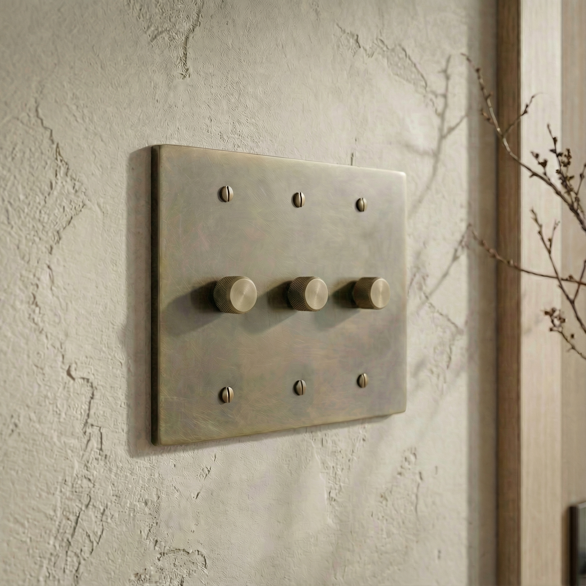Solid antique brass 3 gang dimmer switch plate on a textured wall, exuding quiet luxury.