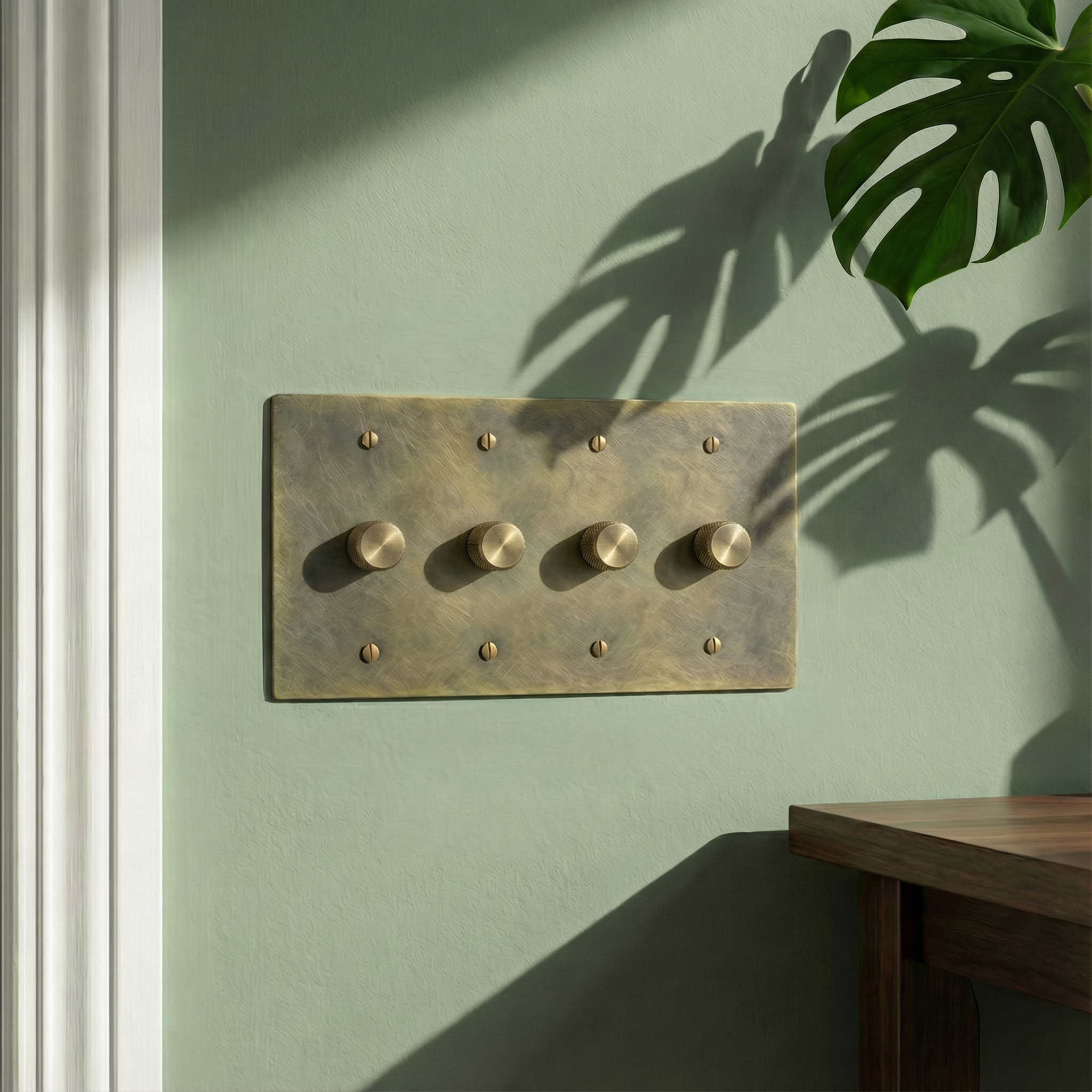 Timeless antique brass 4 gang dimmer switch plate on a muted green wall with plant shadows, exuding quiet luxury.