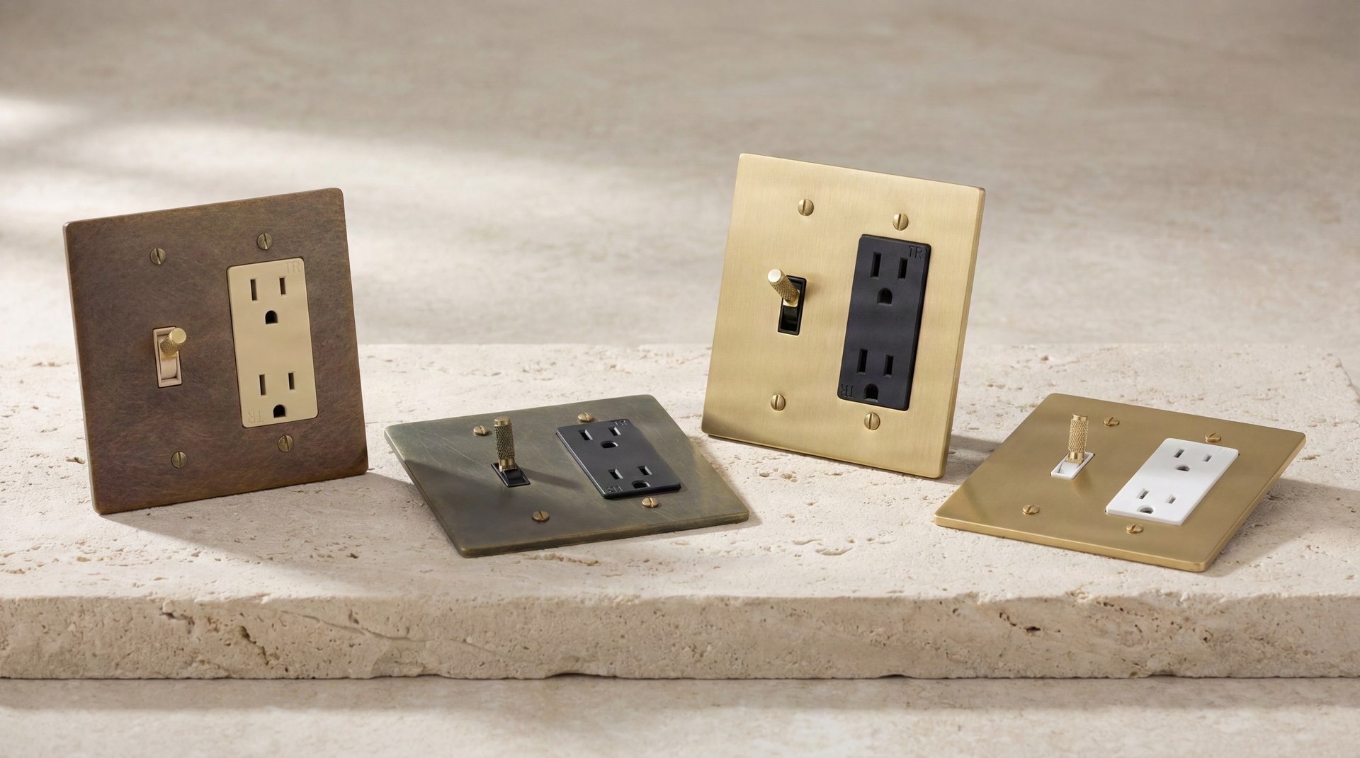 Brass Toggle Switch Outlets with aged and polished finishes, featuring knurled and smooth toggles, on a stone surface. Heirloom quality.