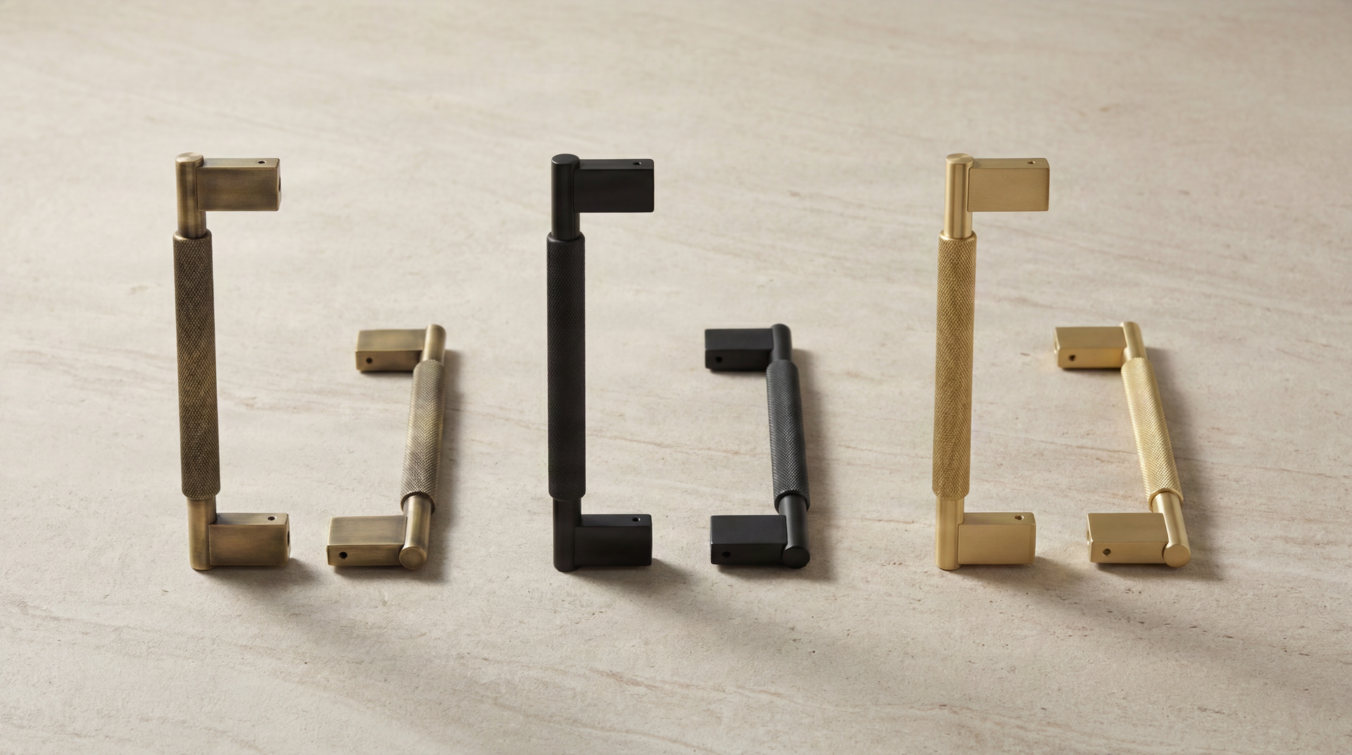 Aged brass, matte black, and satin brass Long Door Pulls (Grassetto) on stone, featuring knurled texture and timeless elegance.