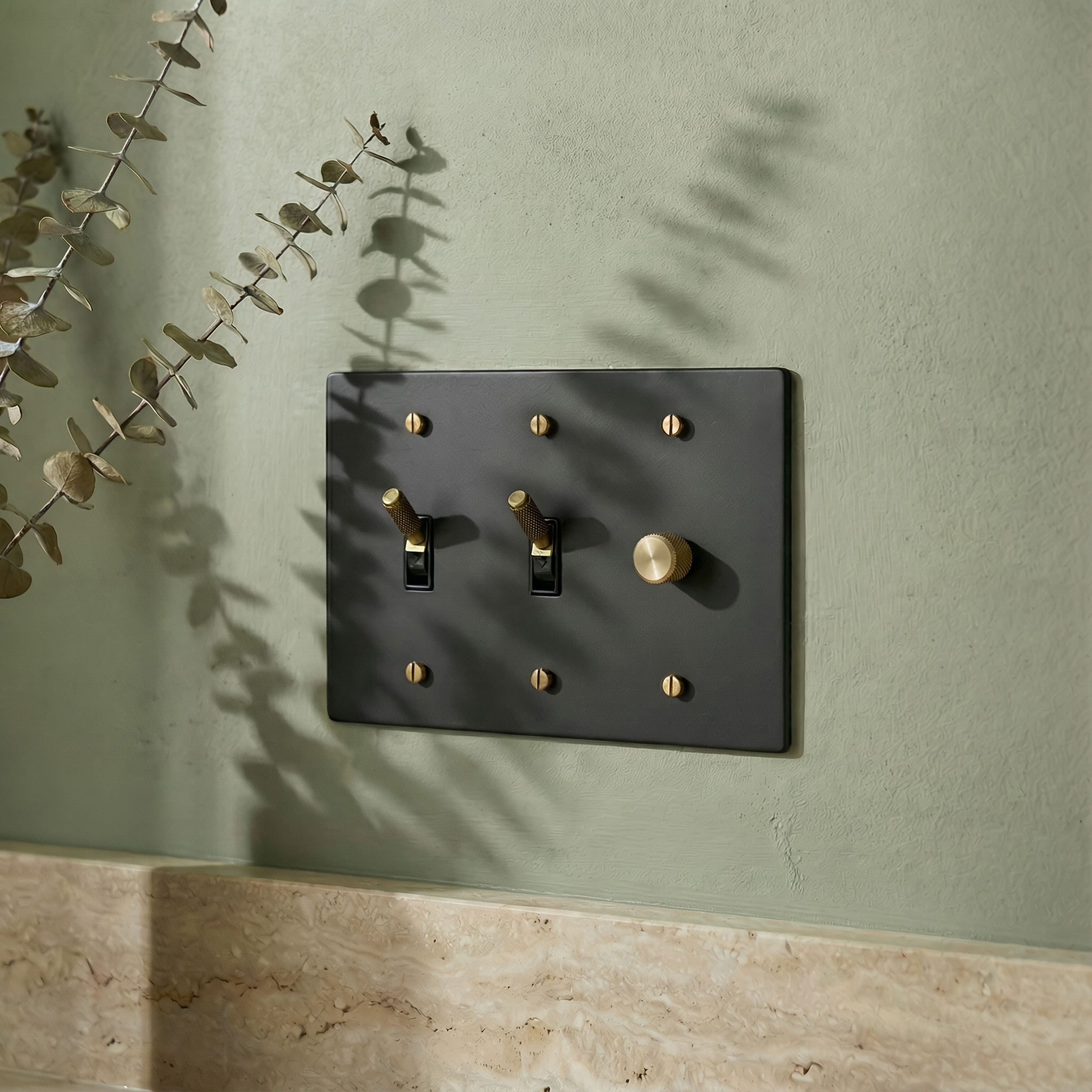 Elegant matte black (antique brass accents) 3 gang dimmer and toggle switch plate complements a sage wall and marble vanity.
