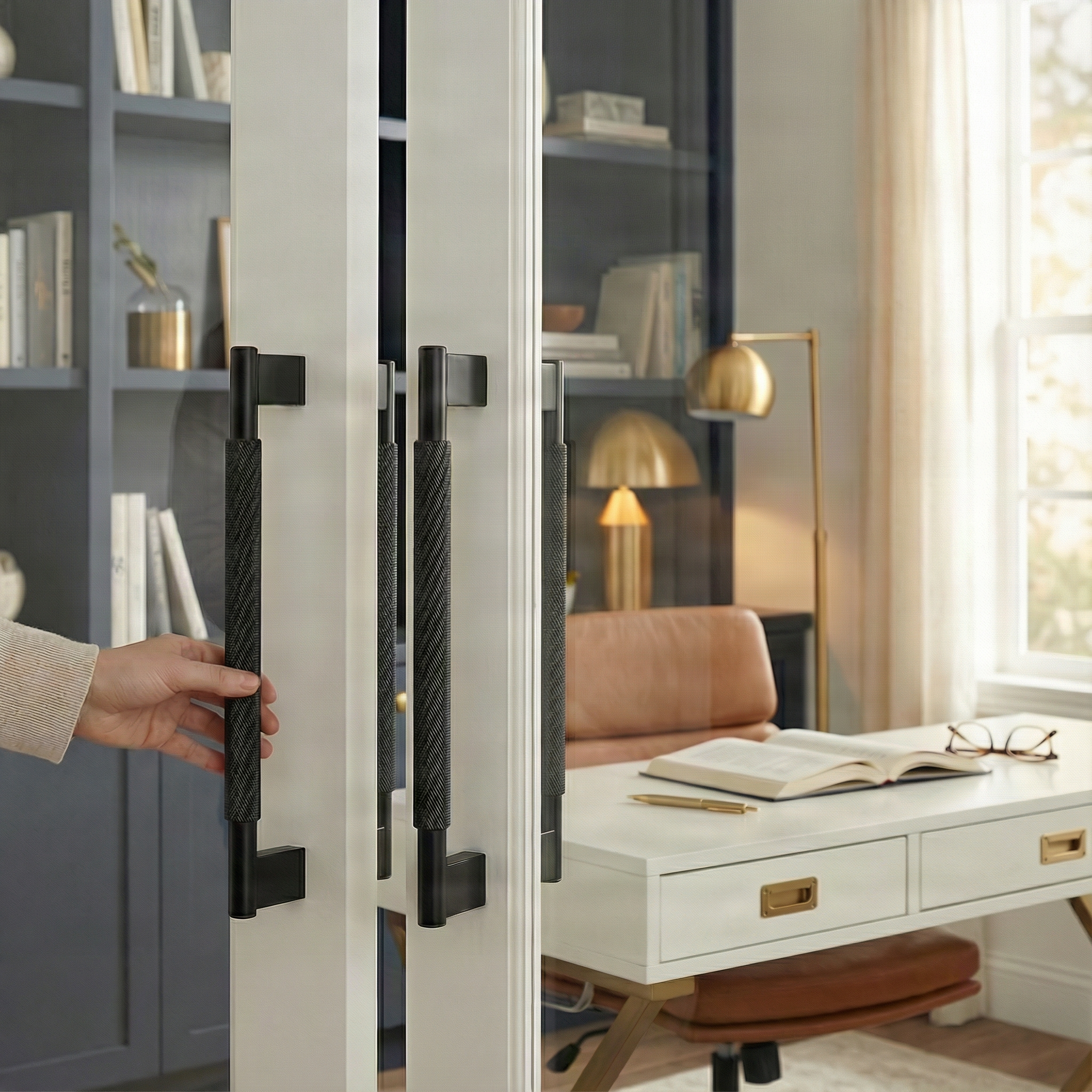Elegant hand grasps a knurled matte black door handle 17 inch on custom cabinetry in a luxurious home office.