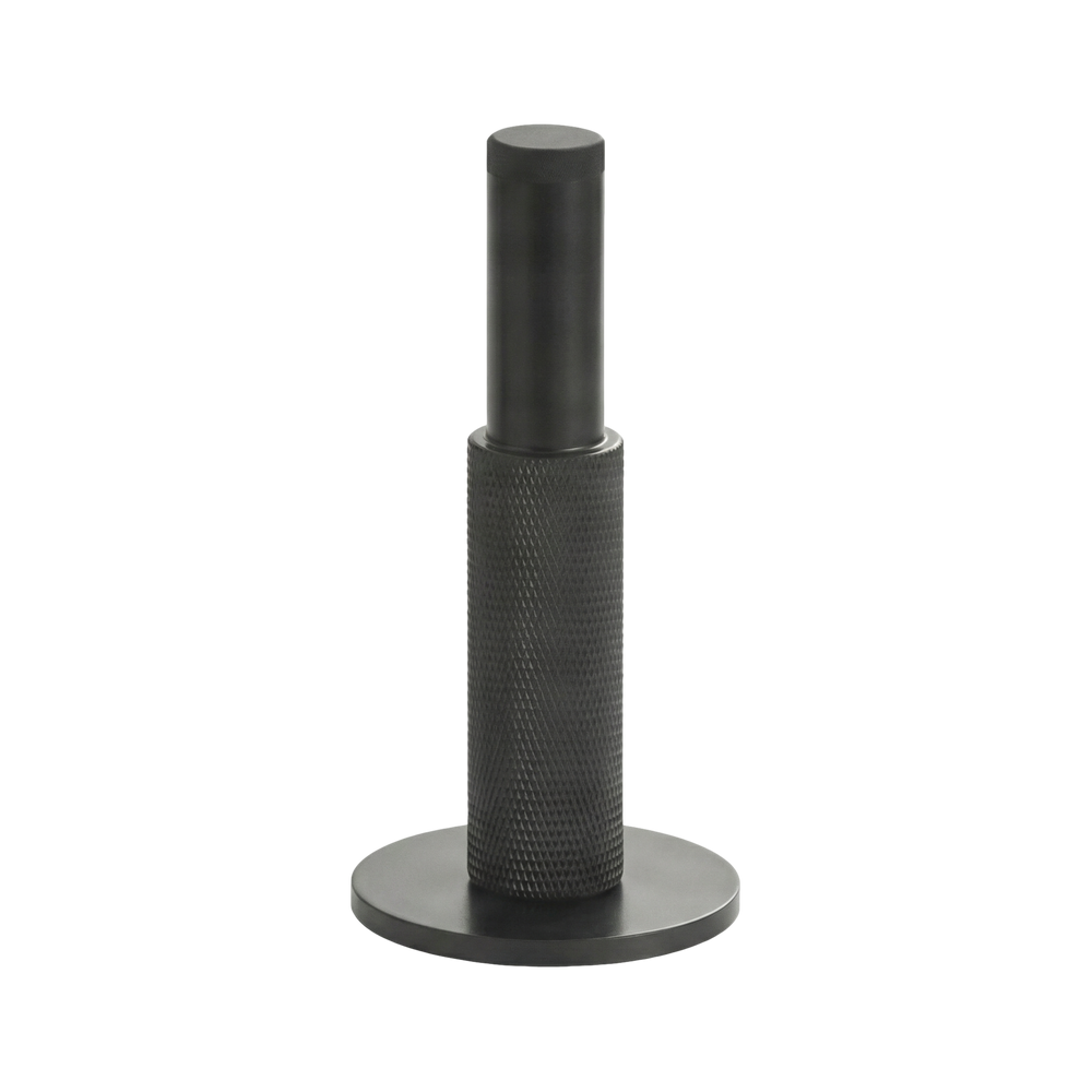 Matte black wall mount door stop with a tactile knurled texture, reflecting timeless minimalist design and solid craftsmanship.