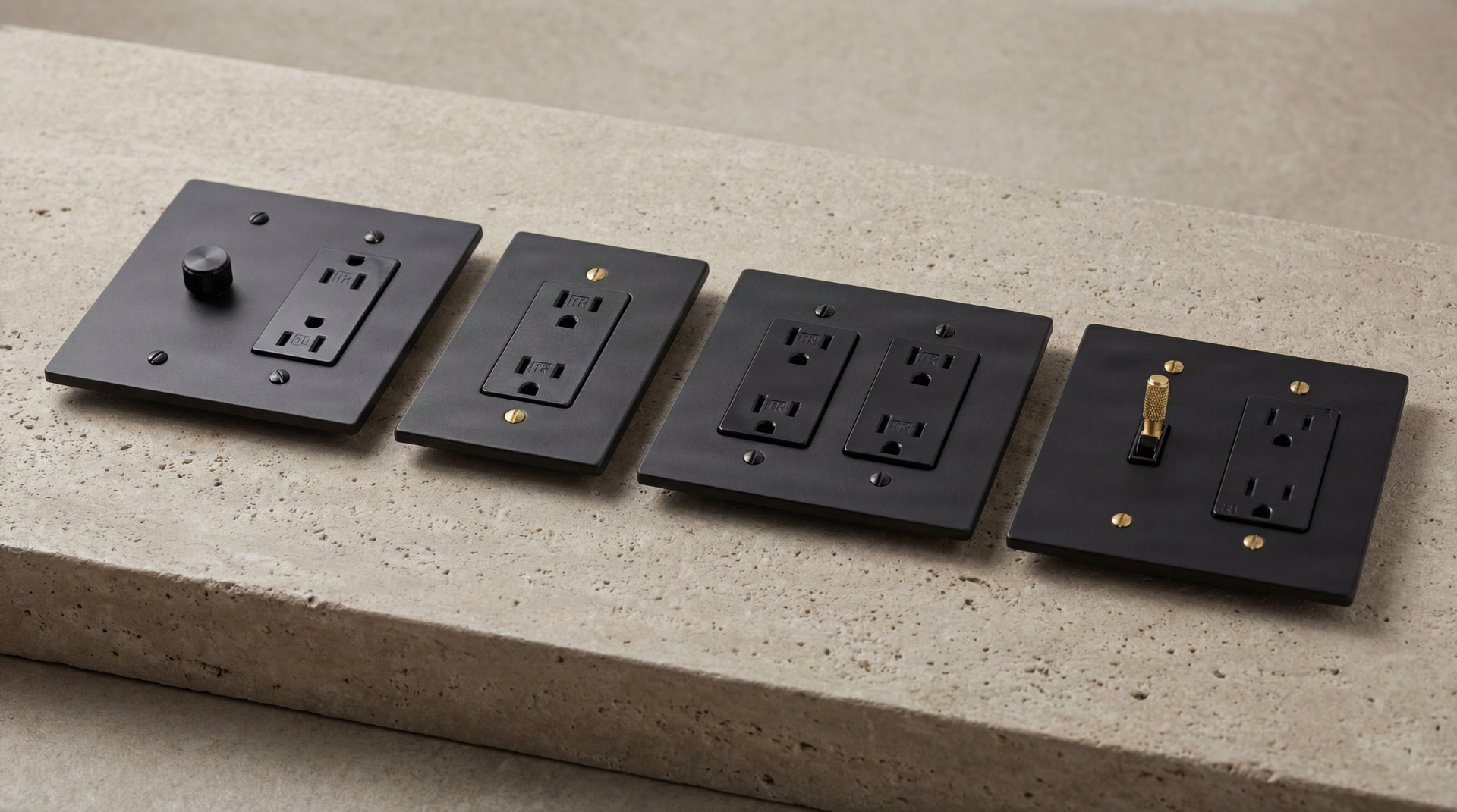 Matte Black Duplex Outlets, a dimmer, and a toggle switch with brass accents on textured stone.