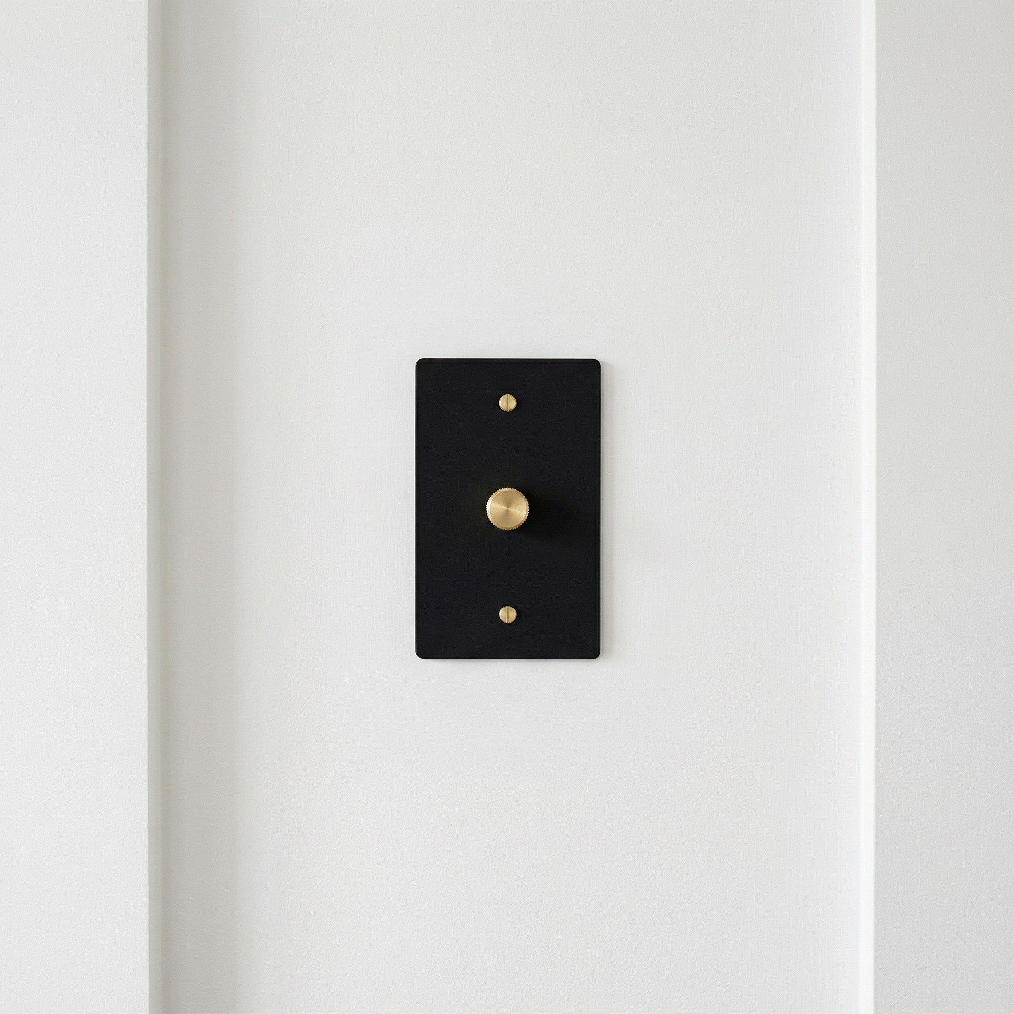 Elegant matte black (satin brass accents) 1 gang dimmer switch plate on a minimalist white wall, exuding timeless luxury.