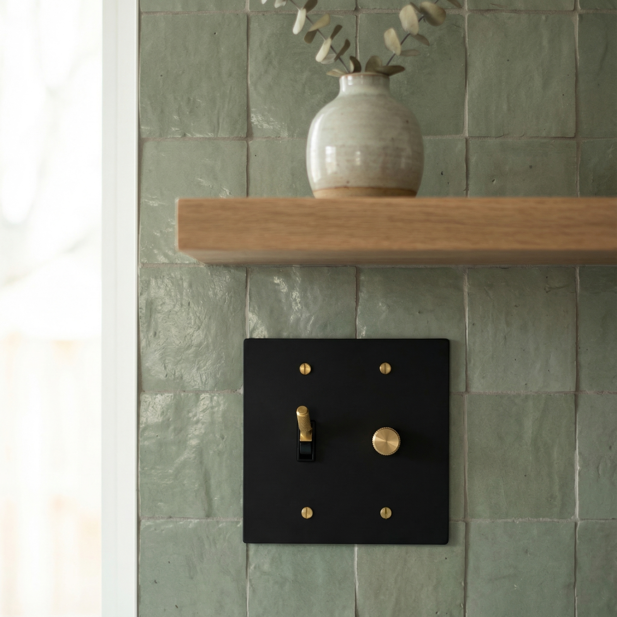 Timeless matte black (satin brass accents) 2 gang dimmer and toggle switch plate on artisan green tiles.