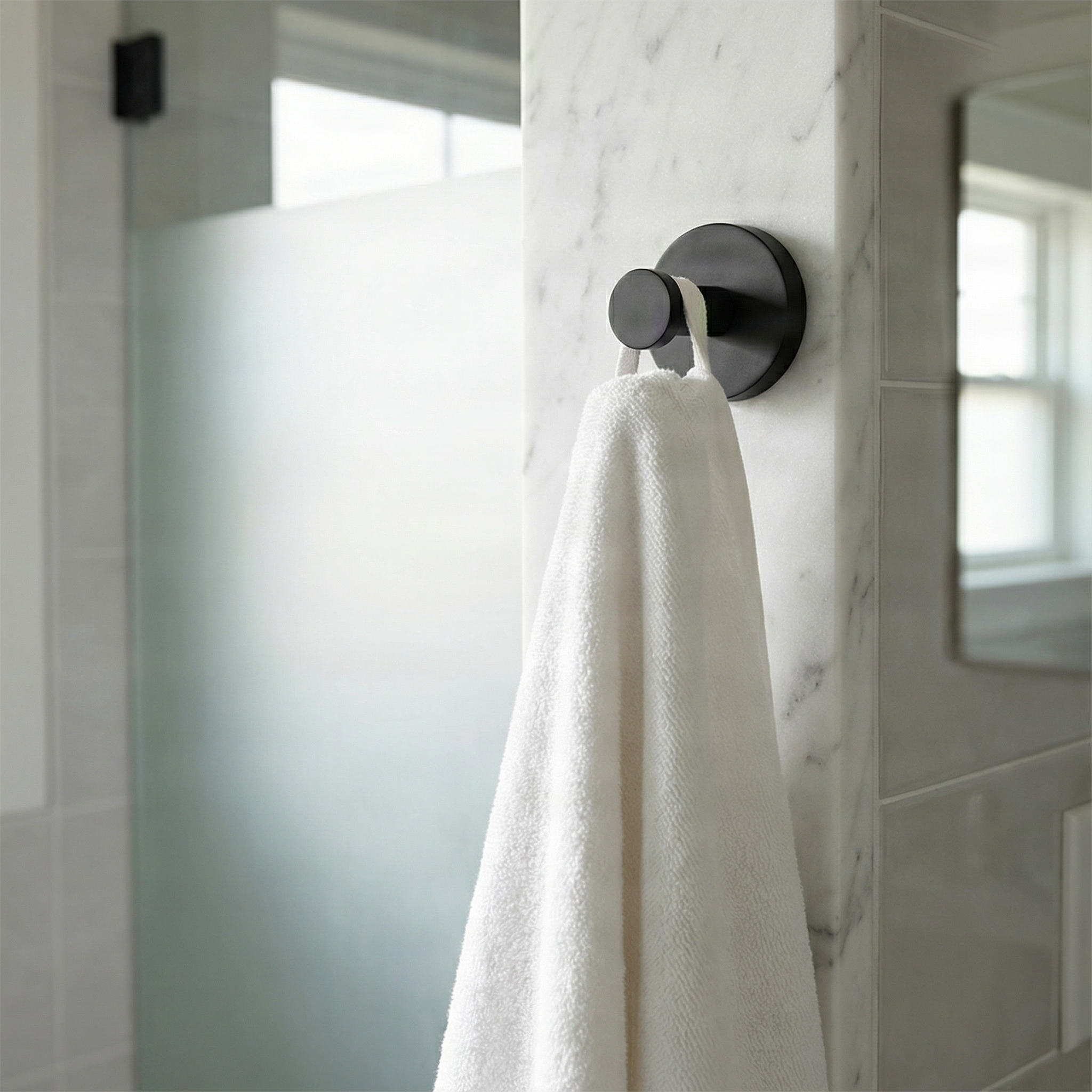 Timeless brass bathroom towel hook on elegant white marble, holding a plush towel in a serene setting.