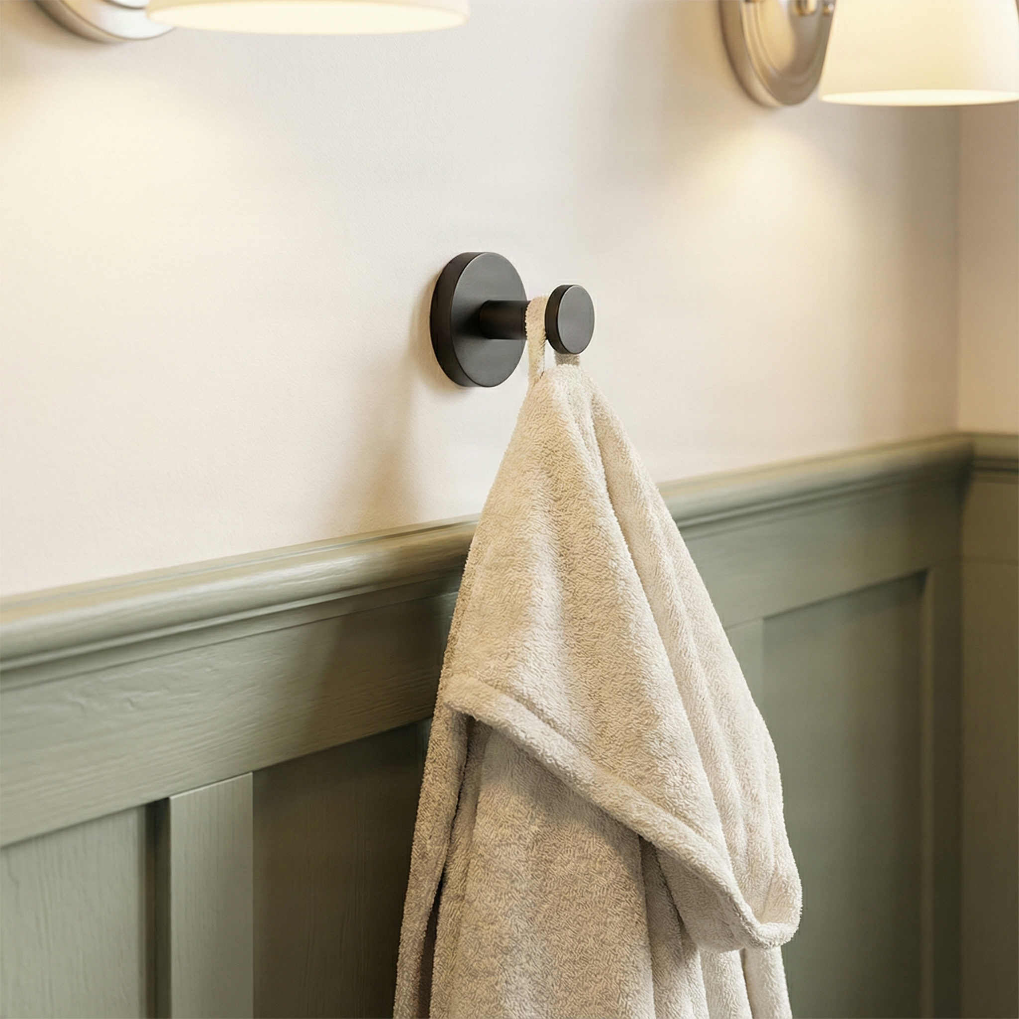 Quiet luxury bathroom showcasing a knurled matte black towel hook and plush robe on a serene sage wall.