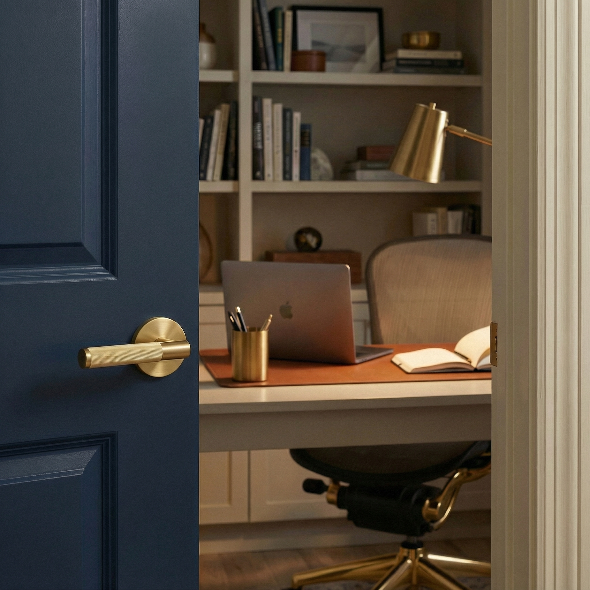 Elegant blue door with knurled modern satin brass lever handle opening to a timeless home office.