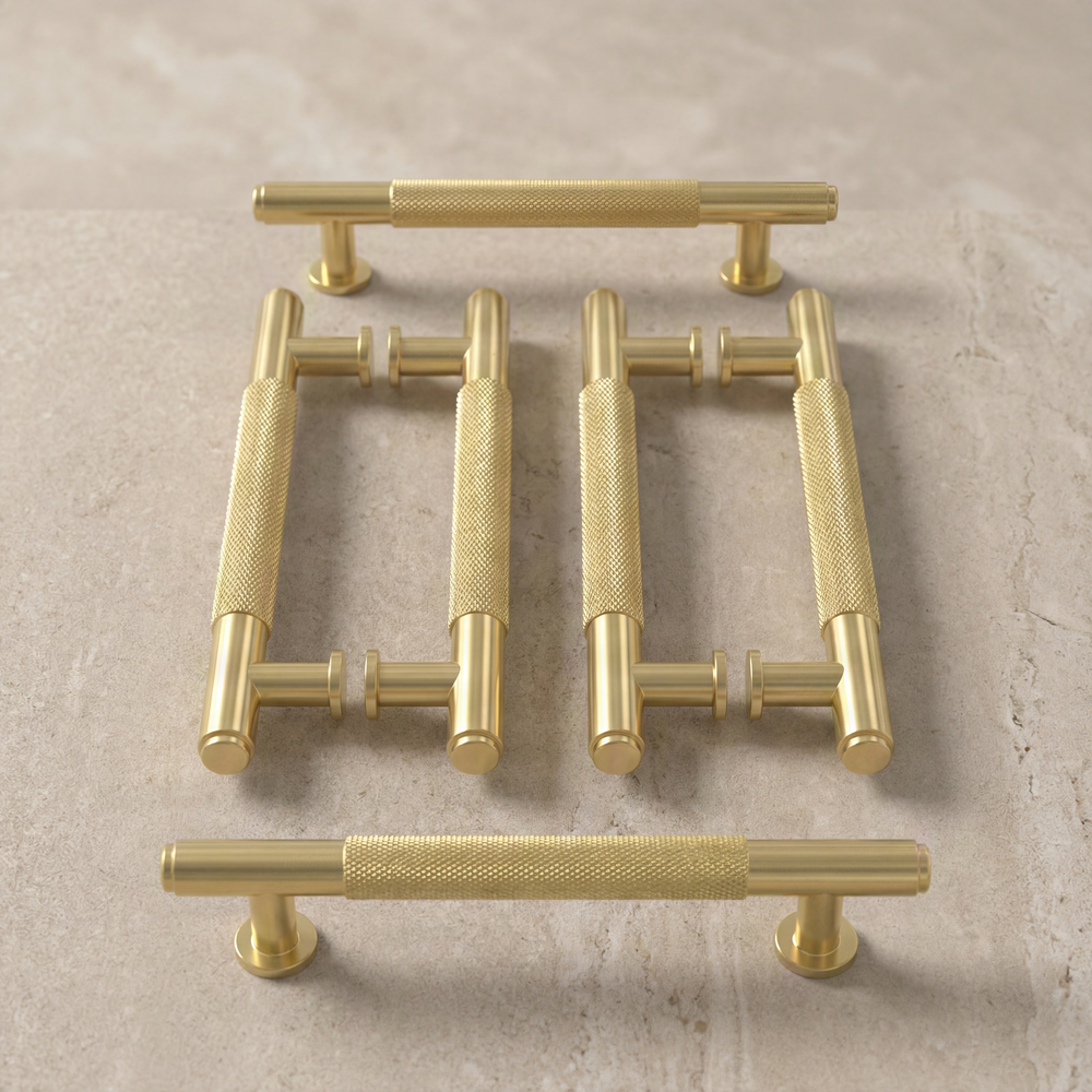 Satin brass door pulls with knurled detail on muted stone.