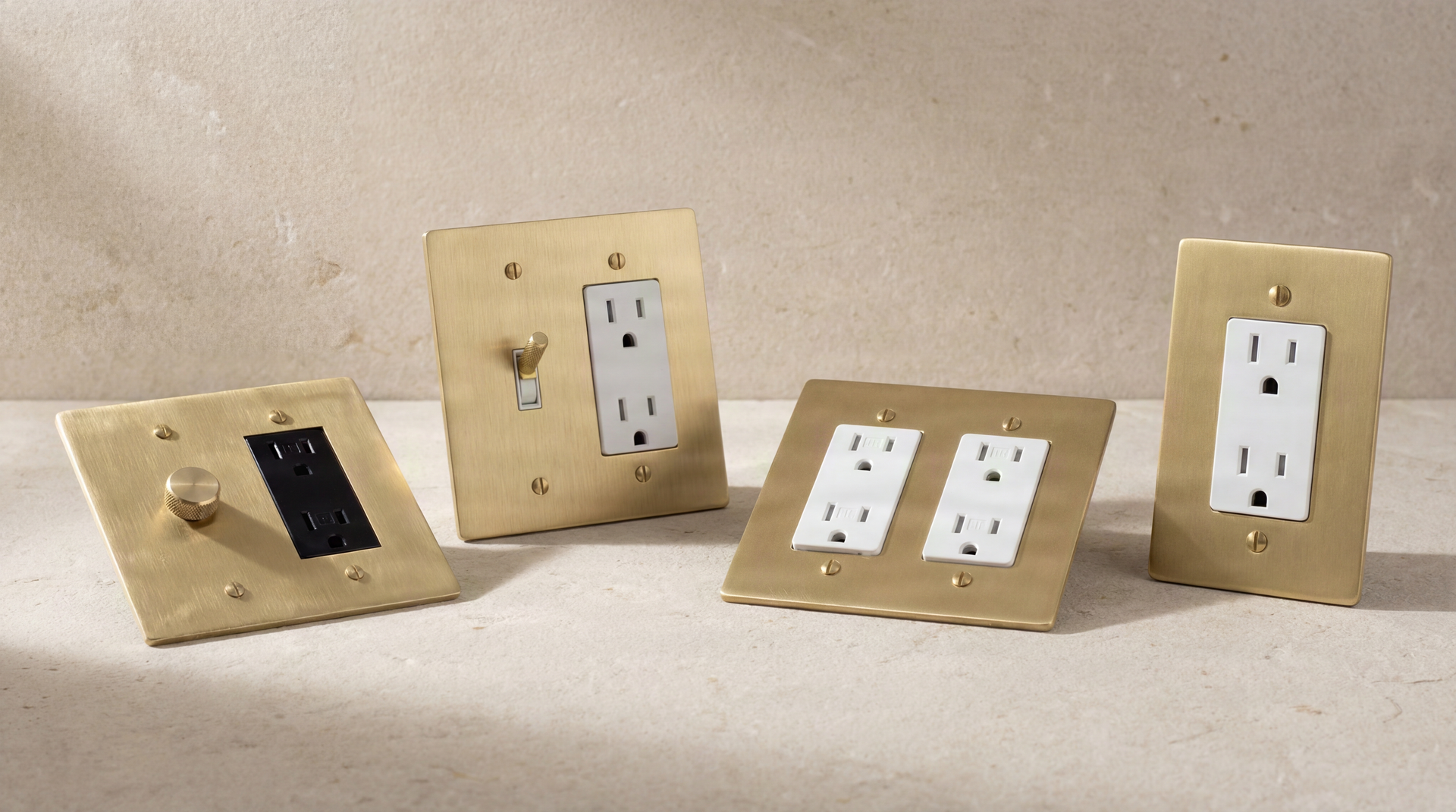 Satin Brass Duplex Outlets and bespoke controls with knurled brass on a textured surface, conveying permanence.