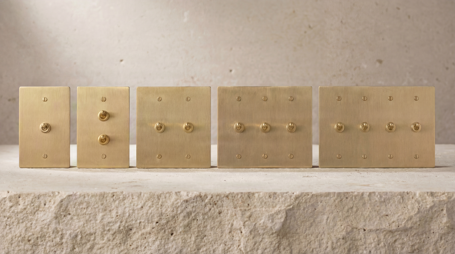 Satin Brass Vintage Toggle Switches in various gang configurations, on natural stone, showcasing lasting craftsmanship.
