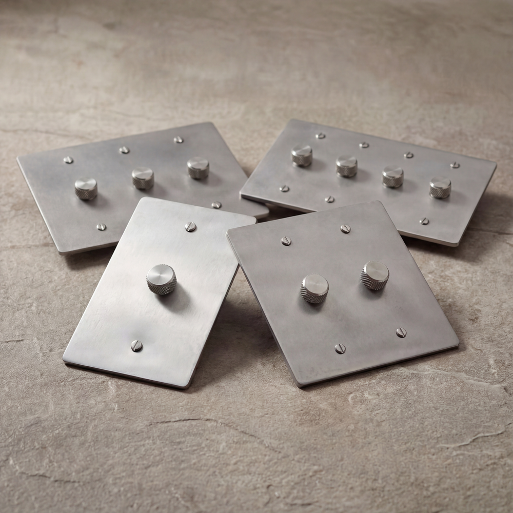 Satin nickel dimmer switches with knurled controls on textured stone.