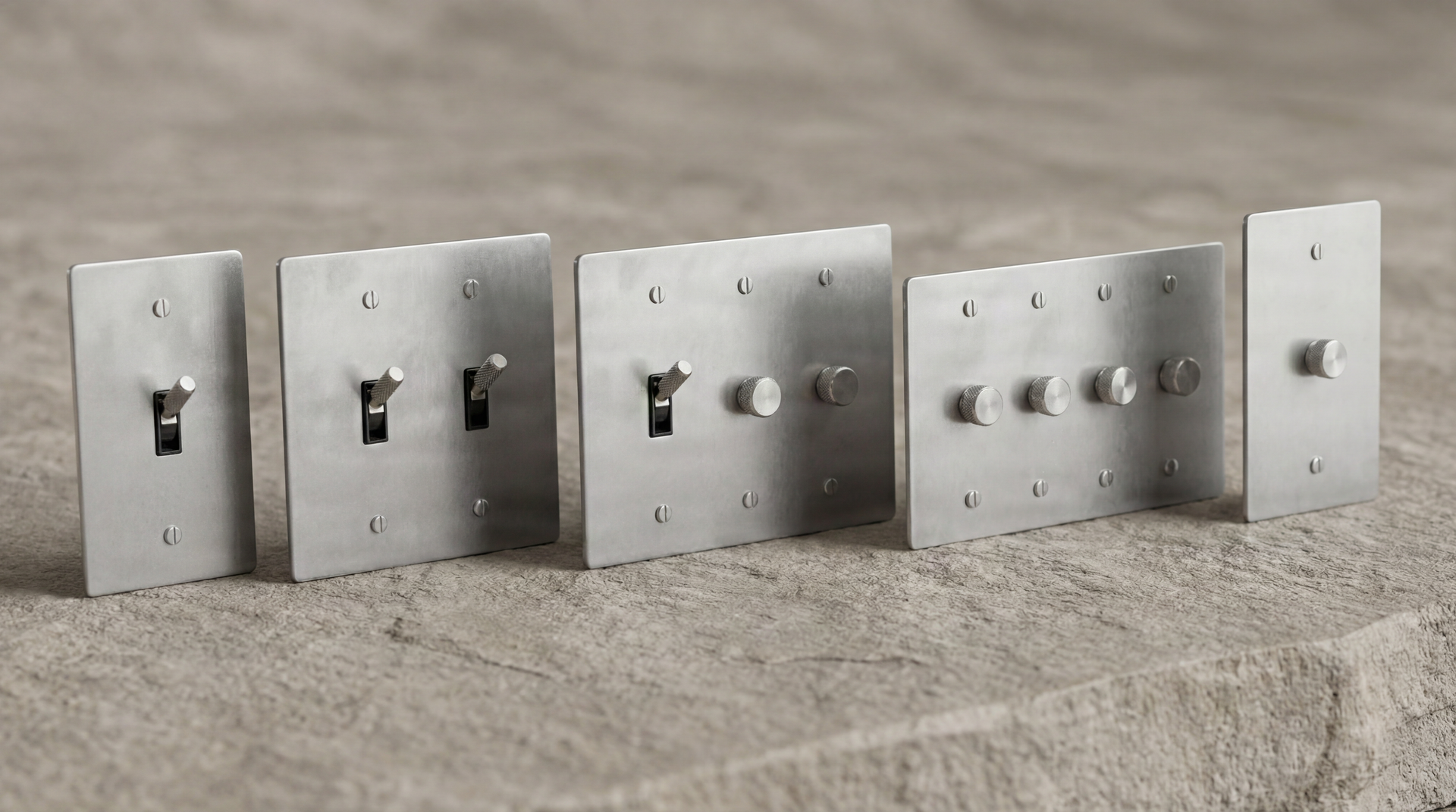 Satin Nickel Light Switches: Custom and multi-gang plates, with knurled toggle and dimmer controls, presented on a natural stone surface.